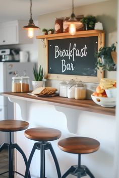 a breakfast bar with three stools and a chalkboard on the wall above it