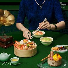 a woman is holding chopsticks over a bowl of food on a green table