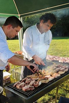 two men grilling meat on an outdoor grill