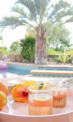 there are three glasses on the table with lemons and oranges next to it