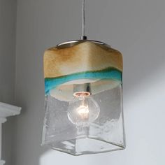 a glass light fixture hanging from a ceiling in a room with white walls and fireplace