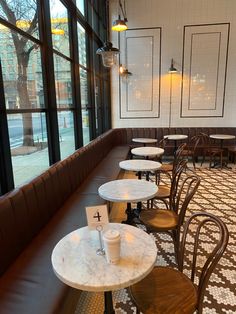 tables and chairs are lined up against the wall in a restaurant with large glass windows