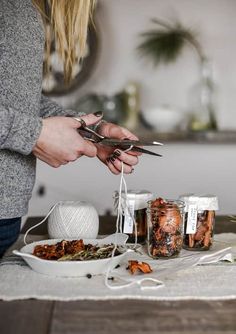 a woman is cutting up some food on a table with scissors and yarn in front of her