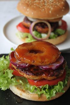 two hamburgers with onion rings and lettuce on them