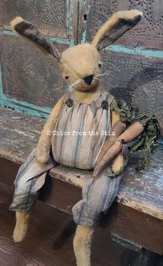 a stuffed rabbit sitting on top of a wooden bench