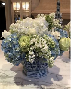 a blue and white vase filled with flowers on top of a marble slabd counter