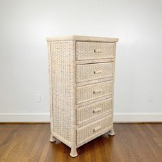 a wicker chest of drawers in a room with hardwood floors and white walls on the wall