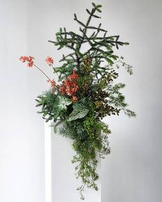 a tall white vase filled with lots of green and red flowers