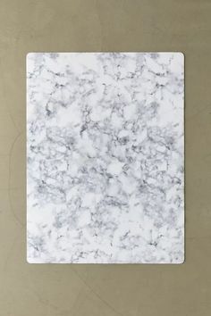 a square marble tile with white and grey veining on the edges, against a beige background