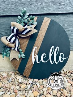 a wooden sign with the word hello painted on it and a ribbon tied around it