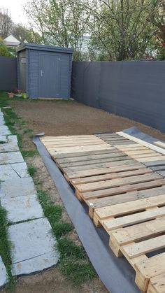 a wooden pallet sitting in the middle of a yard next to a fence and grass