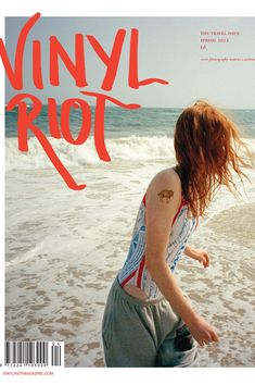 a woman walking on top of a beach next to the ocean with her hair blowing in the wind