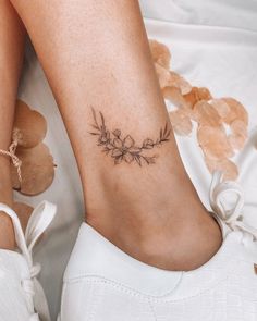 a close up of a person's foot with a flower tattoo on the ankle