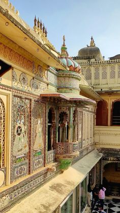 an elaborately decorated balcony in the middle of a building with people walking around it