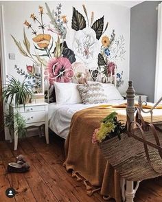 a bedroom decorated with flowers and plants on the wall, along with a wicker basket