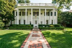 a large white house sitting on top of a lush green field