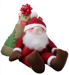 a stuffed santa claus sitting next to a christmas tree with presents in it's pouch