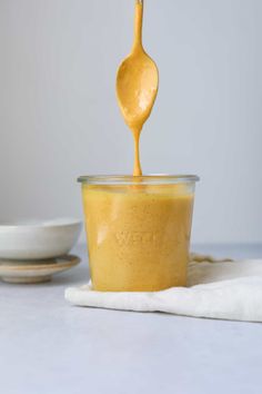 a spoon is pouring peanut butter into a bowl