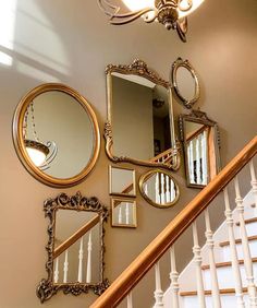 there are many mirrors on the wall next to the bannister and staircase rail