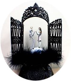 two figurines standing in front of an iron gate with black feathers on it