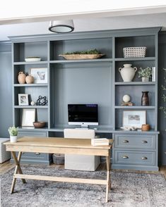 a home office with built in shelving units