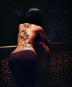 the back of a woman's body is shown with tattoos on her left side