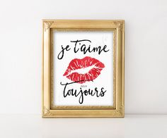 a gold frame with a red lipstick print on it and the words je t'aime taujous written in french