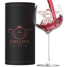 a wine glass is being filled with red wine from the bottle and next to it's packaging