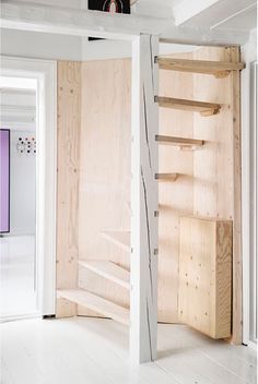 an open door leading to a room with white floors and walls that have wood paneling on them