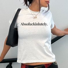 Embrace your inner Y2K vibes with the Absofuckinlutely Baby Tee. This trendy top features a hilarious slogan print and a touch of 90s nostalgia. Don't miss out on the chance to add some fun and personality to your wardrobe with this funny shirt! The model is wearing an XS size. Our size guide ensures a perfect fit. Trendy Stretch T-shirt With Slogan, Funny Quote Print Crew Neck Top, Trendy Stretch Tops With Slogan, Trendy Fitted White Print Top, Funny White Tops For Streetwear, Fitted Fun Slogan T-shirt, Fitted Fun T-shirt With Slogan, Funny Print Crew Neck Top For Streetwear, Fitted Tops With Funny Text