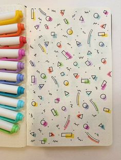 a notebook with markers and pens sitting on top of it