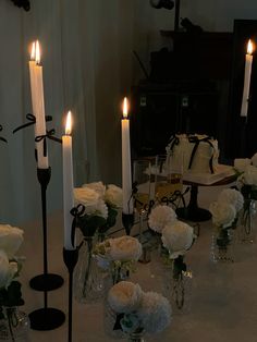 the table is set with candles and flowers in glass vases on which there are white roses