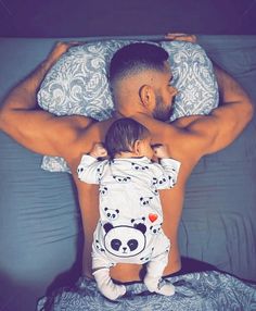 a man holding a baby on top of a bed