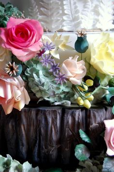 there are many different colored flowers in the vase on the table, including roses and leaves