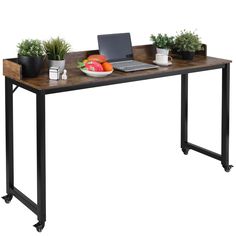 a laptop computer sitting on top of a wooden table next to potted plants and fruit