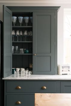 a kitchen with gray cupboards and glassware on the counter top in front of it