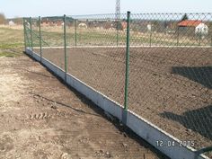 a chain link fence along the side of a dirt field