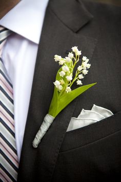 a boutonniere with lily of the valley flowers on it and a striped tie