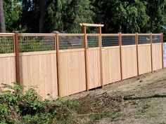 a wooden fence with wire on top and trees in the background