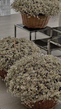 two baskets filled with white flowers sitting on top of a metal table next to each other