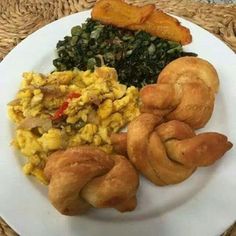 a white plate topped with different types of breakfast foods on top of a woven place mat