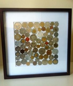 a frame with some coins in it on top of a white table and a wall behind it