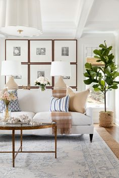 a living room with white couches, pillows and lamps on the wall above them