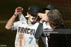 two baseball players with their hands in the air and one is holding something up to his face