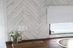 a bathroom with wood flooring and white tile on the wall, along with a sink