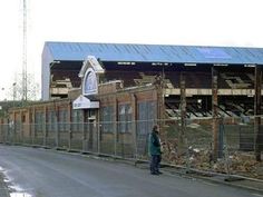 a man standing on the side of a road next to a fenced in area