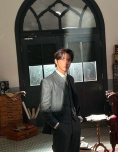 a man in a suit and tie standing next to a chair