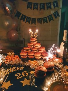 a table topped with lots of donuts covered in frosting and sparklers next to a bottle of wine