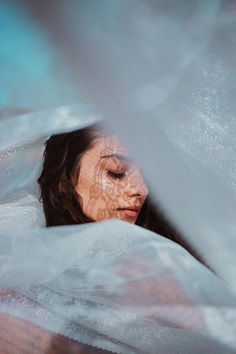 a woman with her eyes closed and covered in white fabric