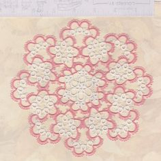 an image of a doily with flowers on the bottom and pink trim around it